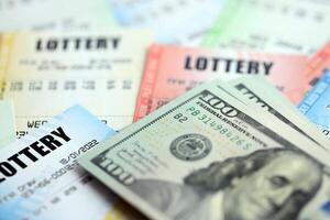 Many lottery tickets and dollar bills on blank bills with numbers for playing lottery photo