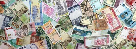 Many banknotes of different currency. Background of big amount of random money bills photo