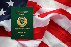 Green Nigerian passport on United States national flag background close up photo