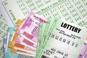 Green lottery tickets and indian rupees money bills on blank with numbers for playing lottery photo