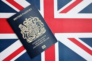 Blue British passport on national flag background close up photo