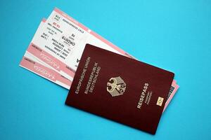 Red German passport of European Union with airline tickets on blue background close up photo