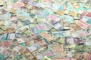 Many banknotes of different currency. Background of big amount of random money bills photo