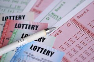 Lottery tickets of different colors and pen on blank bills with numbers for playing lottery photo