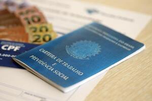 TERNOPIL, UKRAINE - JULY 7, 2023 Brazilian Work Permit document and Brazilian tax number card on table with tax form photo