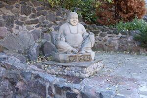 Cherkasy, UKRAINE - OCTOBER 20, 2021 Joyful Buddah concrete grey statue close to White Lotus buddhist temple photo