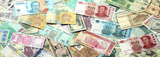 Many banknotes of different currency. Background of big amount of random money bills photo