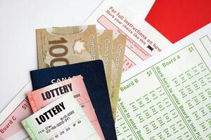 Lottery tickets lies with canadian dollars on gambling sheets with numbers for marking to play lottery photo
