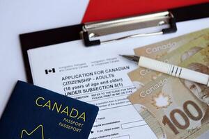 Application for Canadian citizenship for adults on table with pen, passport and dollar bills photo