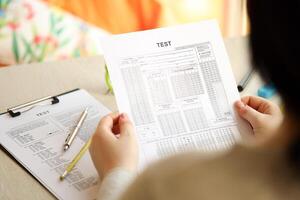 Female student hands testing in exercise and hold exam paper sheet with pencil at school test room photo