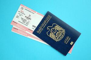 Blue United Arab Emirates passport with airline tickets on blue background close up photo