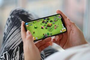 Clash of Clans mobile iOS game on iPhone 15 smartphone screen in female hands during mobile gameplay photo