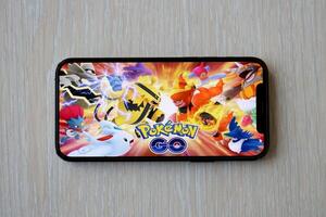 Pokemon GO mobile iOS game on iPhone 15 smartphone screen on wooden table during mobile gameplay photo