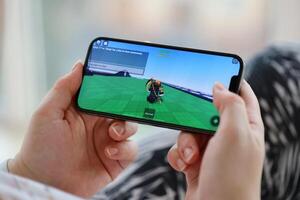 Roblox mobile iOS game on iPhone 15 smartphone screen in female hands during mobile gameplay photo