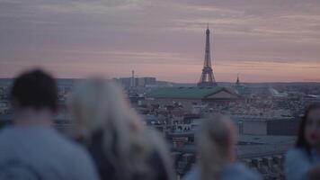 Unrecognizable Tourists on the rooftop of Galeries Lafayette Haussmann enjoying the sunset with the iconic Eiffel Tower and the city buildings of Paris in the background video