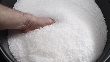 A factory worker checks plastic pellets before they are put into production. White compound in a man's hand. Production video