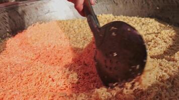 The chef stirs steaming rice in a large pilaf cauldron with a slotted spoon video