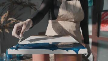 Artist is in her studio, creating a unique abstract painting using blue tones. This is part of the process of designing an interior element. Mid shot. Slow motion video