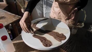 Process of creating an abstract painting using brown epoxy resin is a fascinating one. The craftswoman carefully pours the paint onto the canvas, creating a unique and beautiful piece of art. video