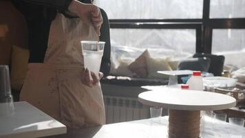 Craftswoman mixes viscous, transparent epoxy resin in her workshop with the help of a stick. Mid shot. Slow motion video