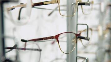 Showcase with spectacles in modern ophthalmic store. Glasses on display on wall in store video