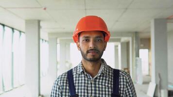 Indian asian builder engineer worker in uniform and helmet walking at construction site of office center video