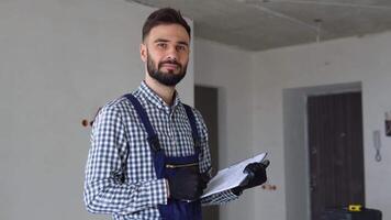 Young foreman builder, engineer or inspector checking and inspecting with clipboard at construction site building interior before complete new project. Contractor and engineering concept video