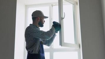 Master installer in overalls installing or adjusting pvc windows in office or apartment. Maintenance service video