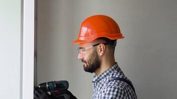 Man in uniform does pvc window installation with a screwdriver in office or apartment. video