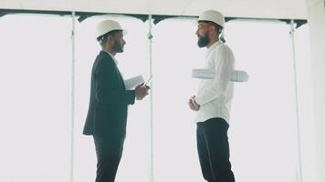 Indian and arabian architects in helmets handshake in a construction site. Two engineer shaking hands with deals and congratulations on success video