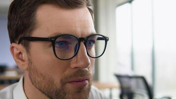 Crypto trader wearing eyeglasses working looking at computer screen reflecting in glasses analyzing online trading stock exchange market financial data charts. Close up eye in spectacles reflection video