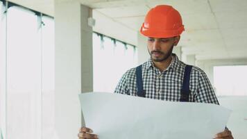Asian indian engineer in uniform and safety helmet looking construction plan in construction site video