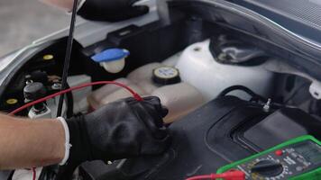 Technician uses multimeter voltmeter to check voltage level in car battery, close up. Service and Maintenance car battery video