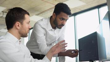 Indian manager consulting client with cryptocurrency or stock market at office meeting. Diverse managers traders analysts discussing financial growth market at desk with pc graphs on screen video