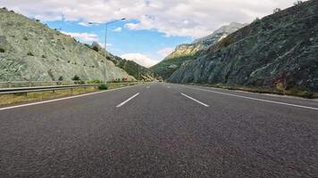 The Majestic Journey. Driving Along a Mountain Highway. A car navigates a wide open road with a breathtaking mountain backdrop in this scenic drive. video