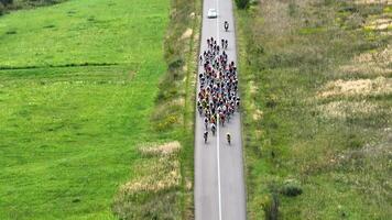 Aerial top view Cycling competition. A group of cyclists taking part in the competition overcomes the distance in the countryside. Riders move in a peloton. video