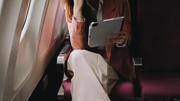 A successful asian businesswoman or female entrepreneur in formal suit in a plane sits in a business class seat and uses a documents with computer laptop during flight video
