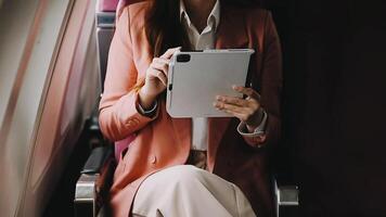 A successful asian businesswoman or female entrepreneur in formal suit in a plane sits in a business class seat and uses a documents with computer laptop during flight video