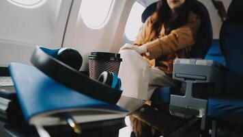 A successful asian businesswoman or female entrepreneur in formal suit in a plane sits in a business class seat and uses a documents with computer laptop during flight video