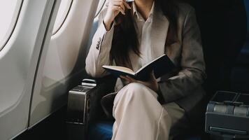 Asian business woman passenger sitting on business class luxury plane while working using notebook book while travel concept. video