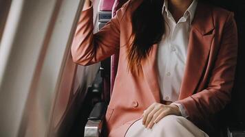 A successful asian businesswoman or female entrepreneur in formal suit in a plane sits in a business class seat and uses a documents with computer laptop during flight video