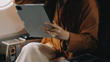 A successful asian businesswoman or female entrepreneur in formal suit in a plane sits in a business class seat and uses a documents with computer laptop during flight video
