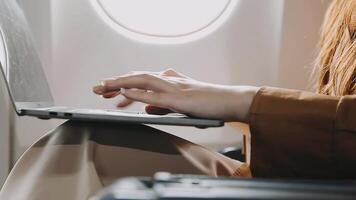 A successful asian businesswoman or female entrepreneur in formal suit in a plane sits in a business class seat and uses a documents with computer laptop during flight video