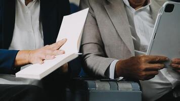 Two businessman passengers sitting in airplane cabin and working on laptop together. Businessman in brown suit showing project on notebook to businessman with eyeglasses. Business and travel concept. video