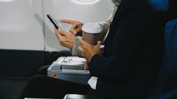Two businessman passengers sitting in airplane cabin and working on laptop together. Businessman in brown suit showing project on notebook to businessman with eyeglasses. Business and travel concept. video