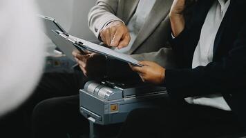 Two businessman passengers sitting in airplane cabin and working on laptop together. Businessman in brown suit showing project on notebook to businessman with eyeglasses. Business and travel concept. video