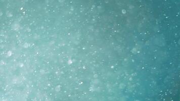 Blurred background of turquoise color and many particles blurred in the air. Imitation of snow on a turquoise background video