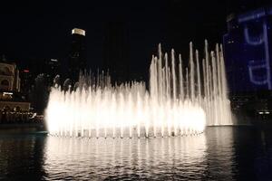 A dancing fountain with lights in Dubai in night photo