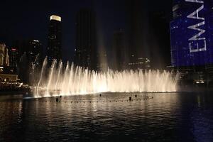 A dancing fountain with lights in Dubai in night photo