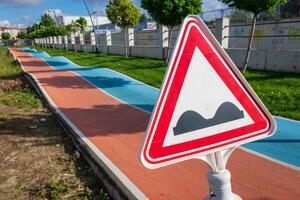 Triangle Safety sign of hilly road in the bicycle academy in Luleburgaz city in Turkey with two way colorful track lane in the background and green nature. Spring time. photo